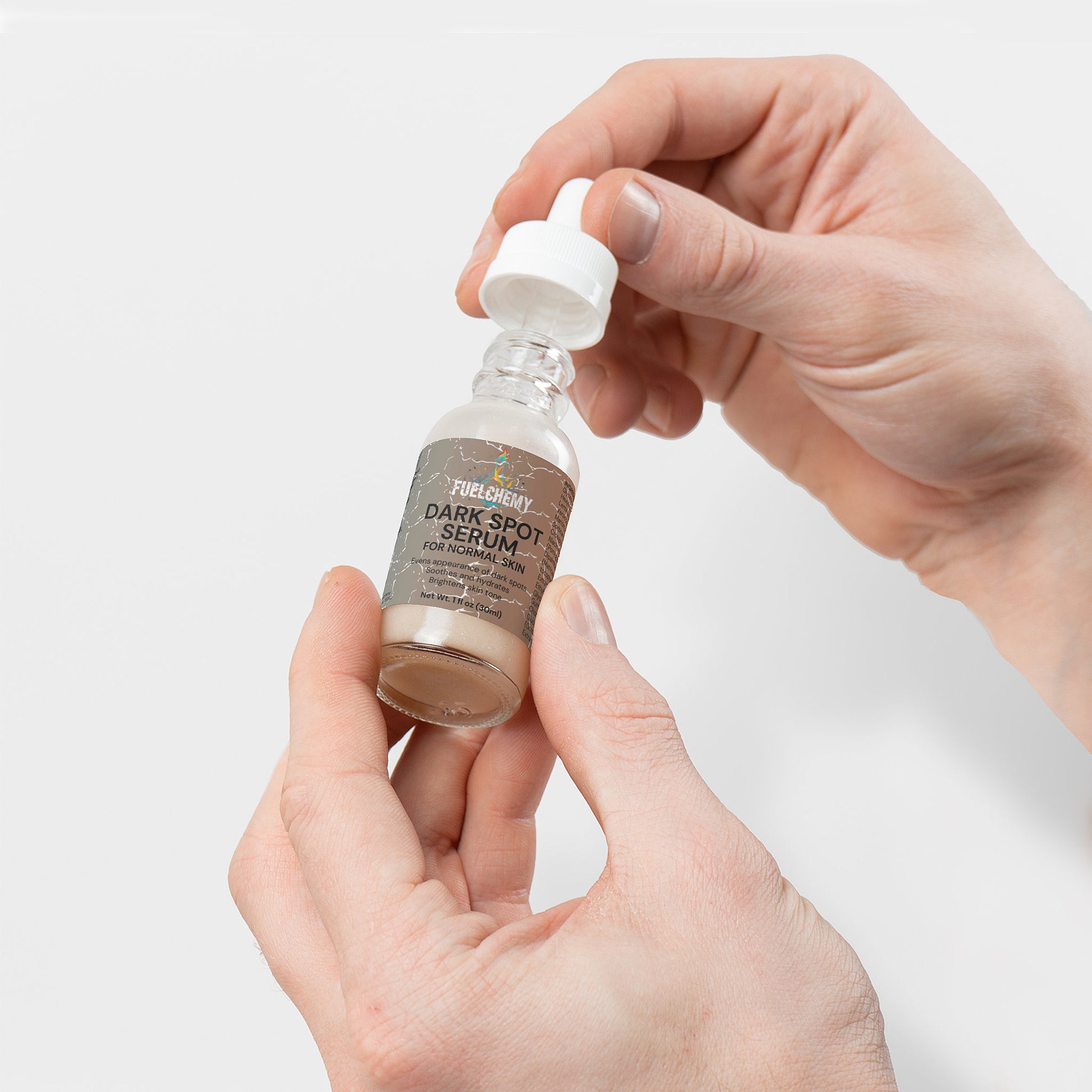 Fuelchemy Dark Spot Serum for Normal Skin in a glass dropper bottle held by hands